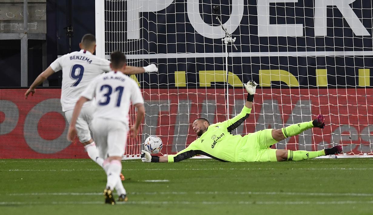 Pemain Real Madrid Karim Benzema (kiri) mencetak gol lewat tendangan penalti ke gawang Cadiz yang dijaga kiper Jeremias Ledesma pada pertandingan La Liga Spanyol di Stadion Ramon Carranza, Cadiz, Spanyol, Rabu  (21/4/2021). Real Madrid menang 3-0. (AP Photo/Jose Breton)