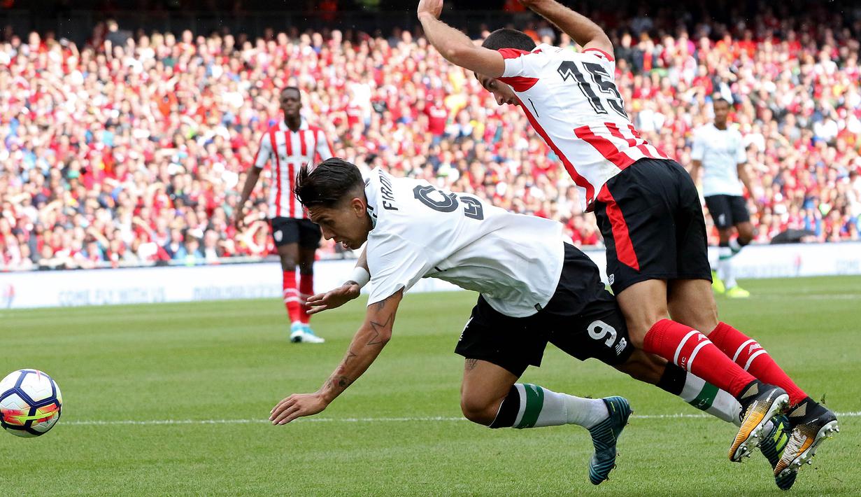 Striker Liverpool, Roberto Firmino, dijatuhkan bek Athletic Bilbao, Inigo Lekue, pada laga persahabatan di Stadion Aviva, Dublin, Sabtu (5/8/2017). Liverpool menang 3-1 atas Athletic Bilbao. (AFP/Paul Faith)