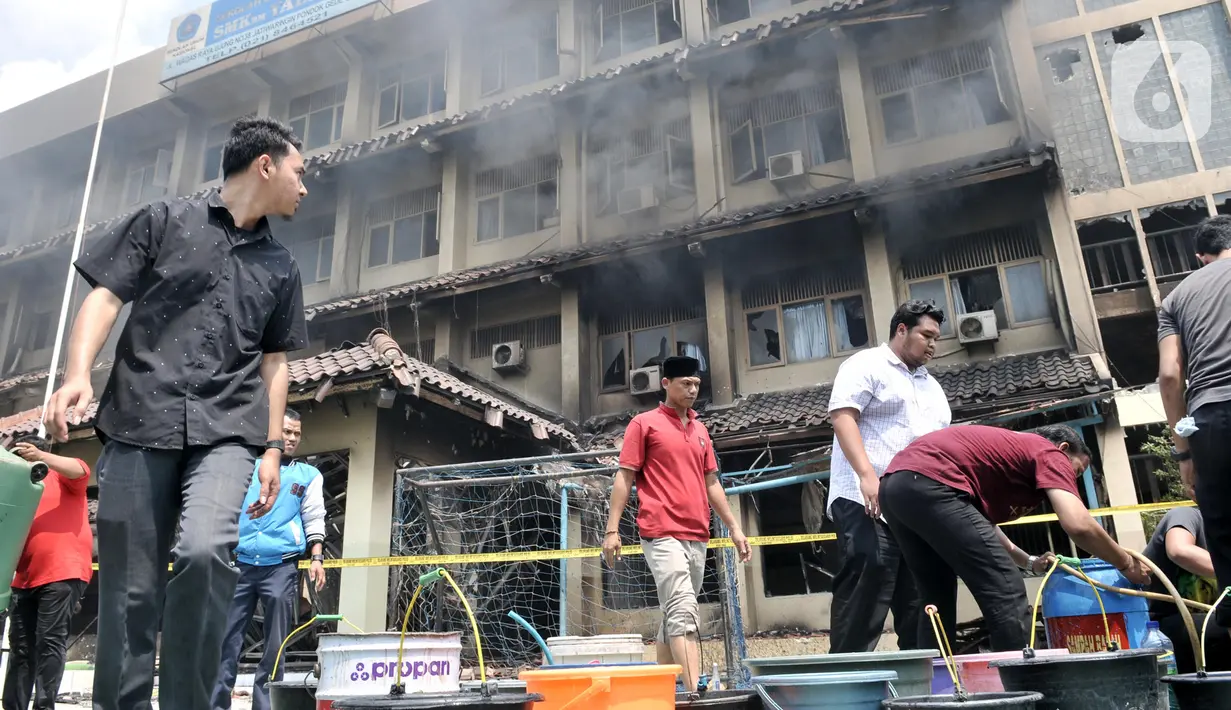 Sejumlah guru, pegawai, dan siswa mengisi air ke dalam wadah saat berusaha memadamkan api yang kembali muncul di Gedung SMK Yadika 6, Jatiwaringin, Pondok Gede, Kota Bekasi, Jawa Barat, Selasa (19/11/2019). Api muncul di salah satu ruang yang berada di lantai 2. (merdeka.com/Iqbal Nugroho)
