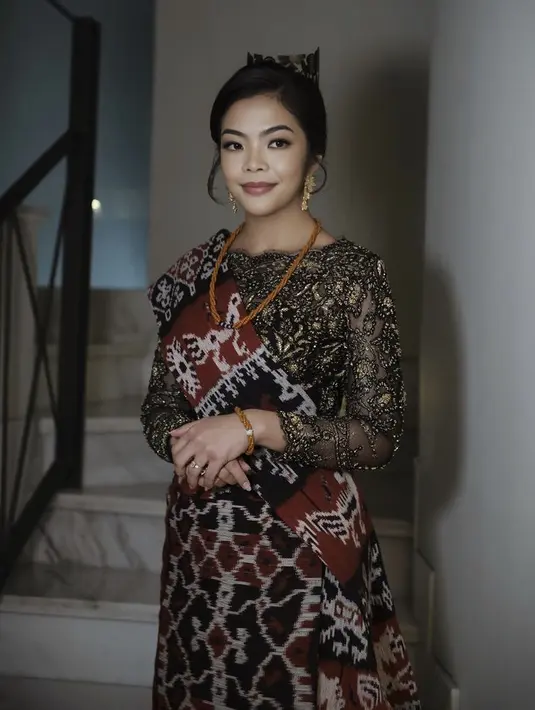 Istri Menteri Olahraga dan Pemuda, Niena Kirana mengenakan kebaya hitam keemasan dari Svarna by Ikat Indonesia dipadukan dengan tenun NTT untuk selendang dan bawahannya. Lengkap dengan aksesori. [Instagram/@ade_ragil_hairdo]