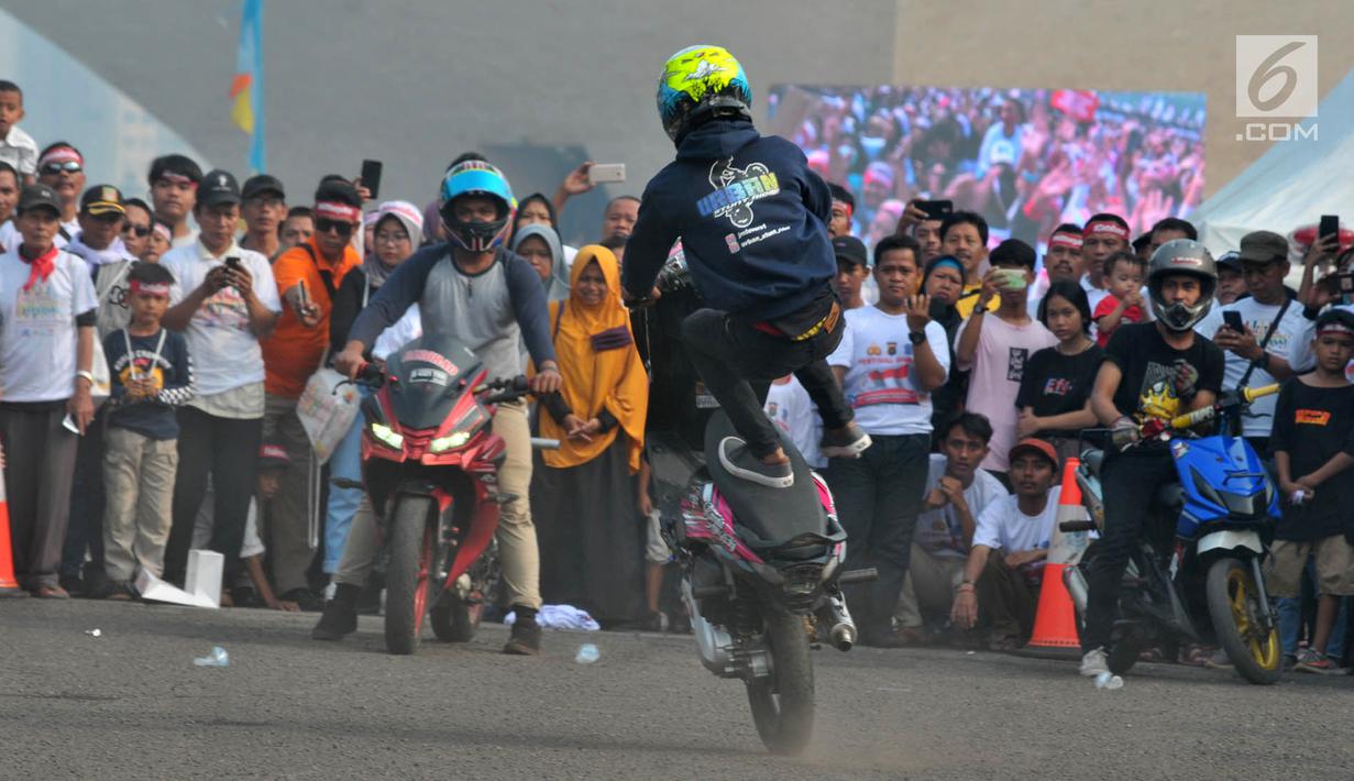 Warga menyaksikan atraksi freestyle sepeda motor saat memeriahkan Festival Damai Millenial Road Safety di Monas, Jakarta, Minggu (23/6/2019). Festival ini juga dimeriahkan oleh berbagai atraksi dan pertunjukan musik artis Tanah Air. (merdeka.com/Iqbal Nugroho)