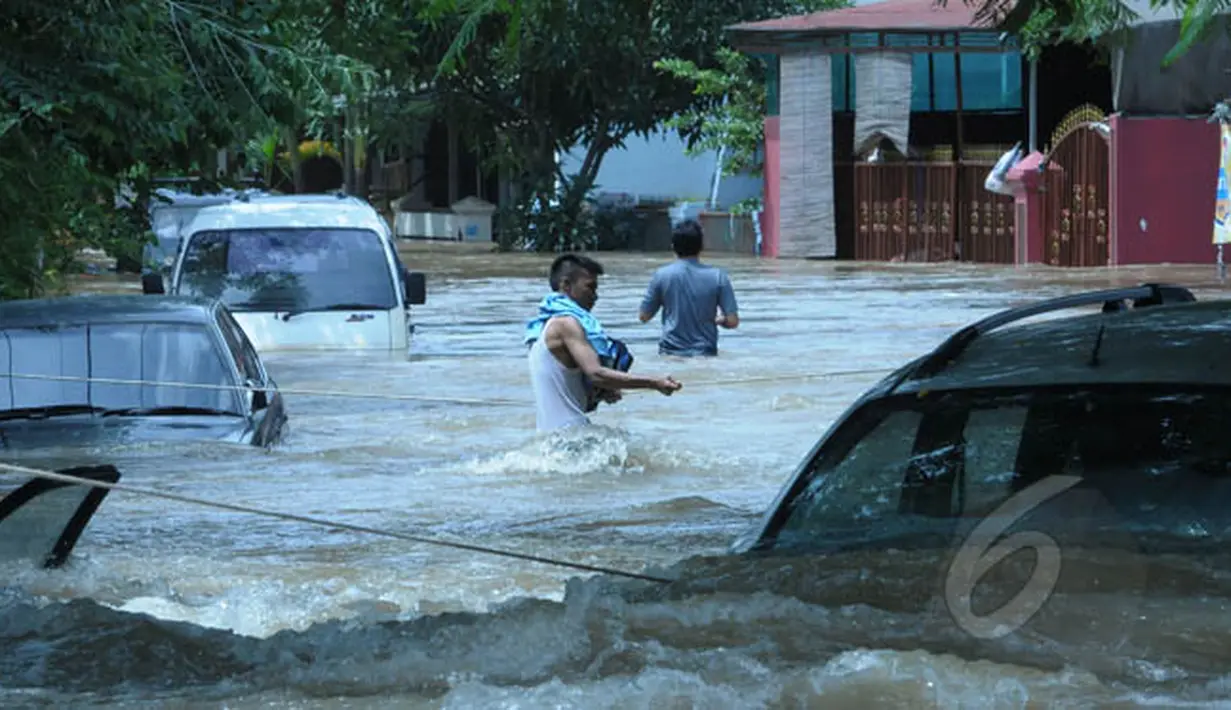 Warga Perumahan Ciledug Indah 1, Tangerang, menyeberangi banjir menggunakan tali untuk menghindari arus deras, Selasa (10/2/2015).(Liputan6.com/Andrian M Tunay)