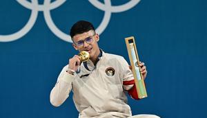 Peraih medali emas dari Indonesia, Rizki Juniansyah, berpose di podium setelah pertandingan angkat besi kelas -73kg putra selama Olimpiade Paris 2024 di South Paris Arena di Paris, pada 8 Agustus 2024. (Miguel MEDINA/AFP)