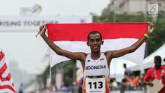 Pelari Indonesia Agus Prayogo membawa Bendera Merah Putih usai melakukan trek maraton SEA Games XXIX di di Putrajaya, Kuala Lumpur, Malaysia, Sabtu (19/8). Agus berhasil meraih medali perak nomor lari marathon cabang atletik. (Liputan6.com/Faizal Fanani)