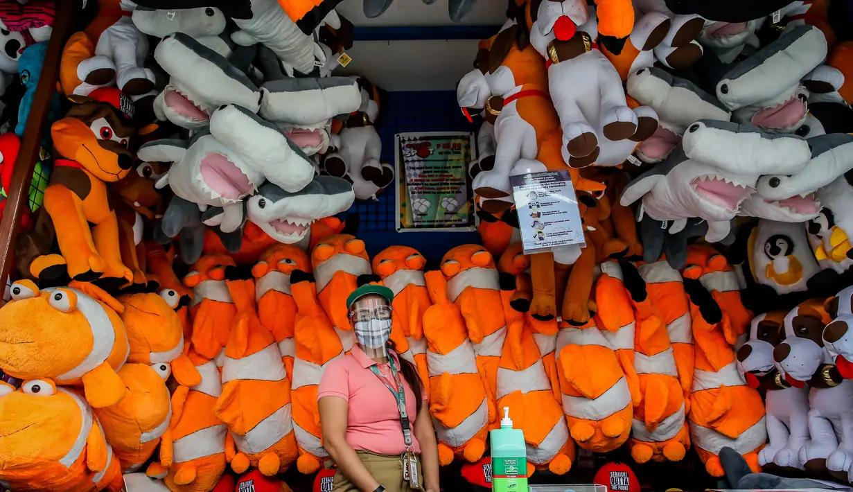 Seorang staf yang mengenakan masker terlihat di sebuah stan permainan mini di taman hiburan Enchanted Kingdom di Provinsi Laguna, Filipina (18/10/2020). Taman hiburan tersebut kembali dibuka untuk pengunjung. (Xinhua/Rouelle Umali)