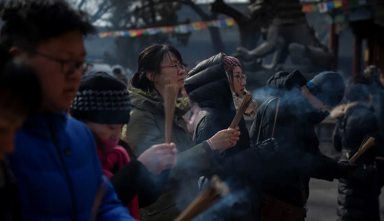 Sejumlah warga berdoa untuk keberuntungan pada hari kelima Tahun Baru Imlek di Yonghegong, atau Kuil Lama di Beijing (9/2). Warga China di seluruh dunia menyambut Tahun Babi pada 5 Februari.  (AFP Photo/Nicolas Asfouri)