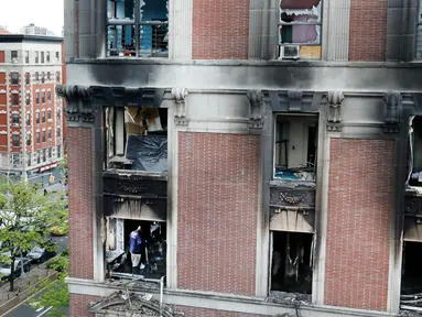 Petugas pemadam kebakaran memeriksa apartemen yang terbakar di kawasan Harlem, New York, Amerika Serikat, Rabu (8/5/2019). Kebakaran tersebut menewaskan enam orang termasuk di antaranya empat anak-anak. (AP Photo/Richard Drew)