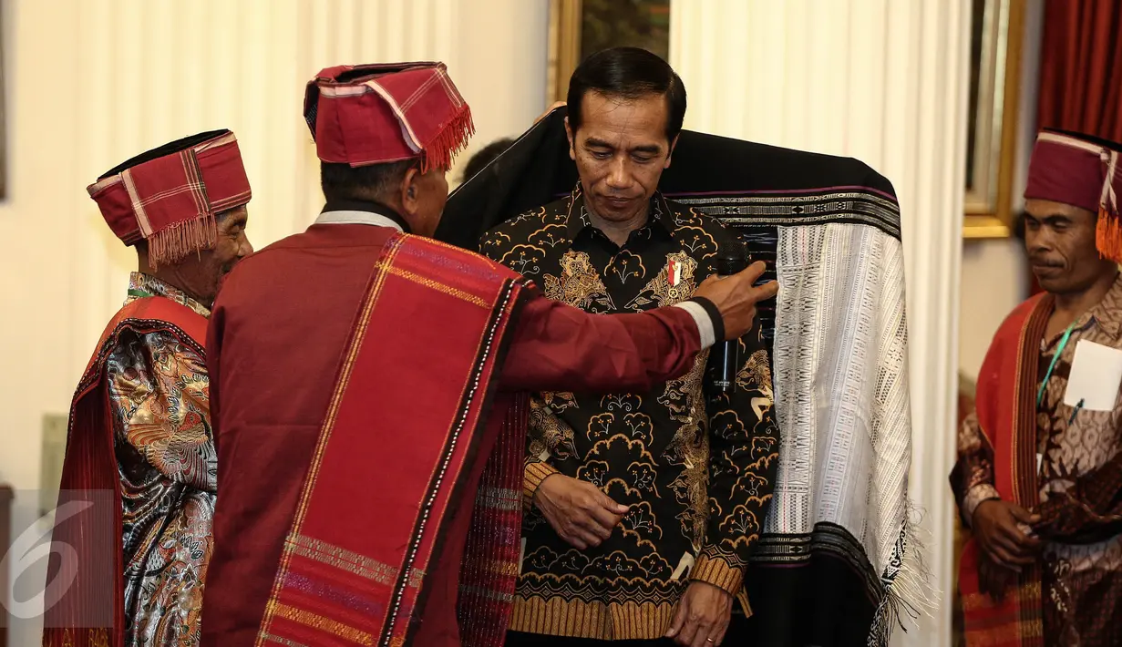 Pemangku Hutan Adat dari Tombak Haminjon (Kemenyan) Provinsi Sumatera Utara saat akan mengalungkan kain ulos kepada Presiden Joko Widodo (Jokowi) usai pencanangan pengakuan Hutan Adat di Istana Negara, Jakarta, Jumat (30/12). (Liputan6.com/Faizal Fanani)
