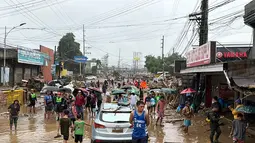Diketahui, badai tropis Penha menghantam daratan di Provinsi Surigao del Sur di Tenggara dari Samudra Pasifik pada Kamis 5 Februari 2026 malam. Tampak dalam foto, warga berjalan menerobos genangan air yang dibawa oleh Badai Tropis Penha di Iligan, provinsi Lanao del Norte, Filipina, pada Jumat 6 Februari 2026. (Merlyn Manos/AFP)