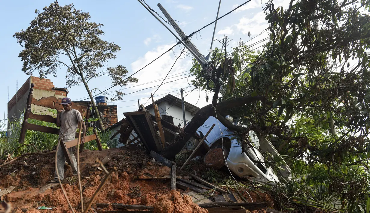 Seorang warga membawa tempat tidur kayu yang dibongkar setelah tanah longsor akibat hujan lebat di Belo Horizonte, Brasil (27/1/2020). Lebih dari 30.000 orang terlantar akibat hujan lebat di Brasil tenggara yang juga menewaskan lebih dari 50 orang. (AP Photo/Gustavo Andrade)