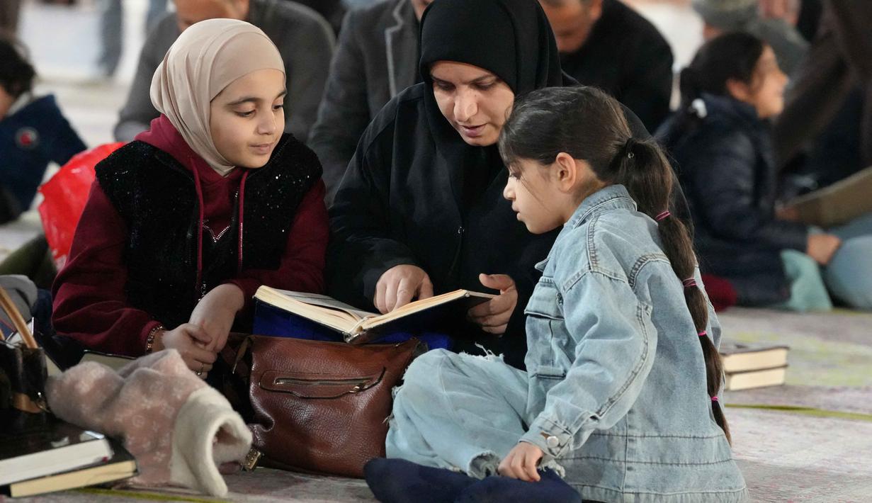 Diketahui, membaca Al Quran menjadi salah satu amalan utama untuk mendapatkan kemuliaan malam yang lebih baik dari seribu bulan tersebut. Tampak dalam foto, seorang wanita Muslim Syiah dan putrinya membaca Al-Quran, membaca Al-Quran, saat melaksanakan Itikaf di Masjid Kufa, selatan Baghdad, Irak, pada 12 Maret 2026. (Qassem al-KAABI/AFP)