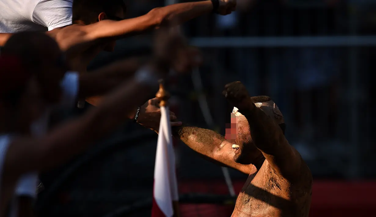 Pemain dengan wajah berdarah menghampiri pendukungnya saat merayakan kemenangannya dalam pertandingan Calcio Storico Fiorentino di Piazza Santa Croce di Florence, Italia (24/6). (AFP Photo/Filippo Monteforte)