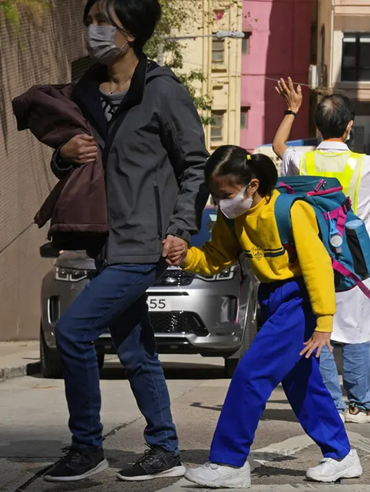 Seorang siswa sekolah dasar berjalan di Hong Kong, Selasa (11/1/2022). Dalam upaya membatasi penularan COVID-19 varian Omicron, Hong Kong mengumumkan penutupan taman kanak-kanak (TK) dan sekolah dasar (SD) setelah infeksi dilaporkan terjadi di kalangan siswa. (AP Photo/Kin Cheung)