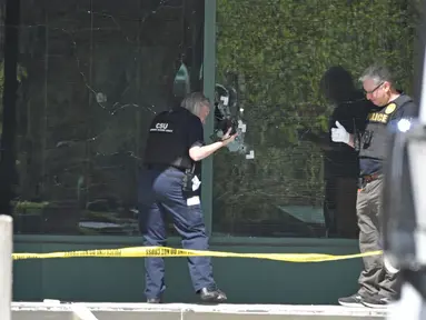 Seorang teknisi Polisi Metro Louisville memotret lubang peluru pada kaca depan Gedung Old National Bank di Louisville, Kentucky, Amerika Serikat, Senin (10/4/2023). (AP Photo/Timothy D. Easley)