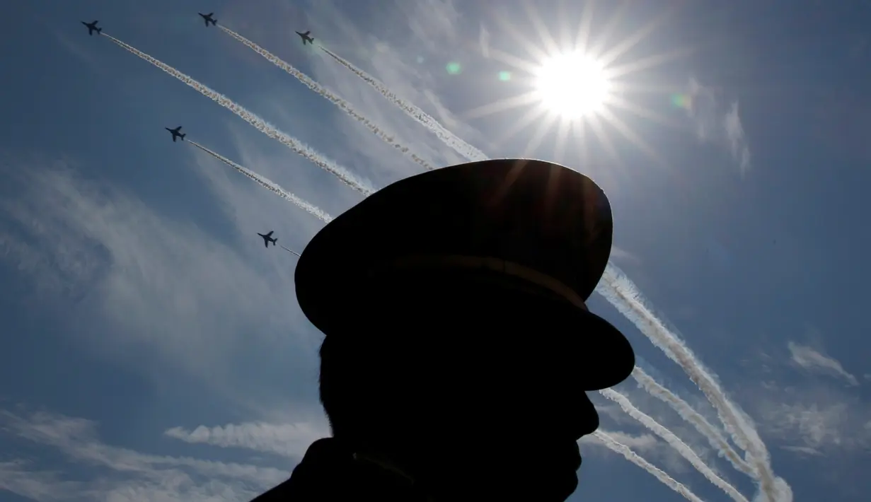 Siluet Angkatan Bela Diri Jepang (SDF) dengan latar belakang pertujukan akrobatik pesawat udara Jepang saat upacara tahunan Pasukan Bela Diri (SDF) di Pangkalan Asaka, Jepang(23/10). (Reuters/Kim Kyun-Hoon)