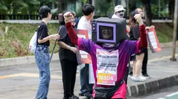 Seorang peserta lari menggunakan kostum berbentuk televisi dalam ajang Run for Journalism 2025 yang berlangsung di Unika Atma Jaya, Jakarta, Minggu (16/11/2025). (Bola.com/Bagaskara Lazuardi)