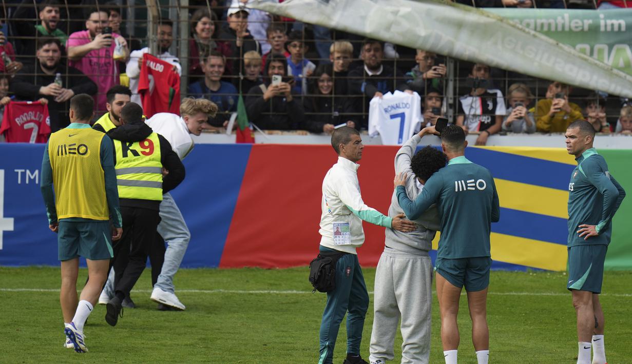 Para penyerbu lapangan terlihat mengangkat ponsel saat pihak keamanan menghentikan langkah mereka. (AP Photo/Hassan Ammar)