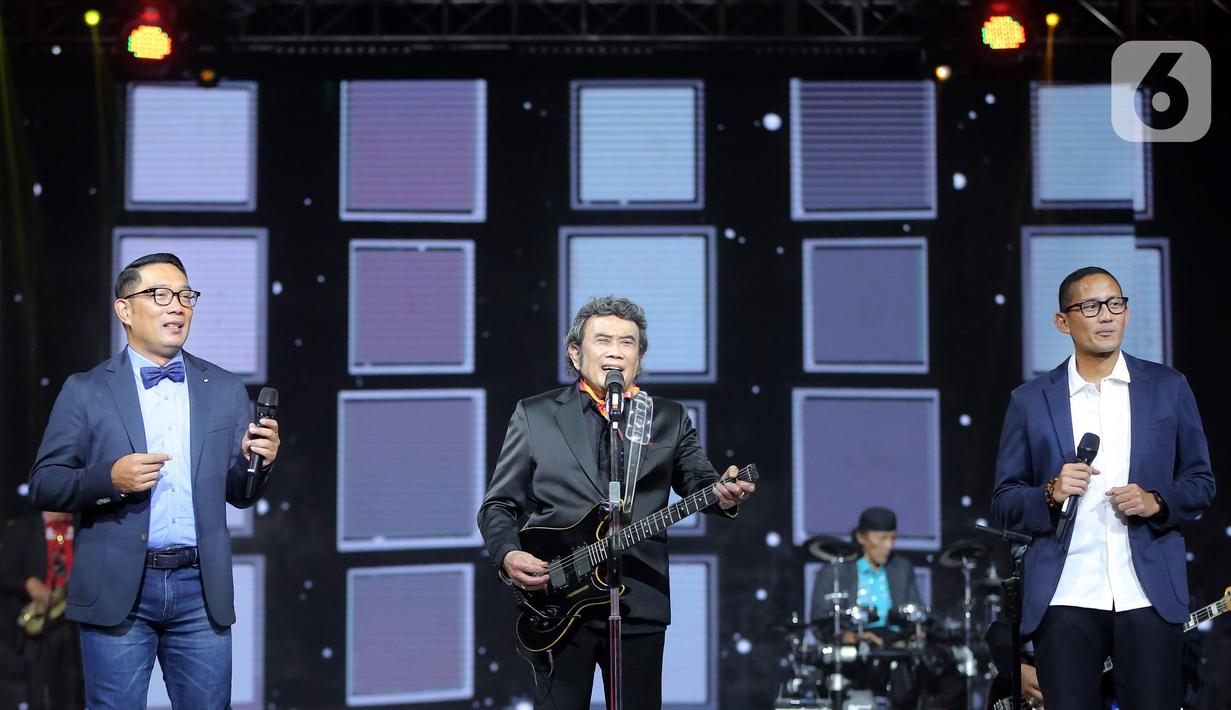 Penyanyi dangdut Rhoma Irama (tengah) tampil bersama Menteri Pariwisata dan Ekonomi Kreatif Sandiaga Uno (kanan) dan Gubernur Jawa Barat Ridwal Kamil (kiri) pada acara HUT ke-28 Indosiar di Studio 6 EMTEK City, Jakarta, Rabu (11/1/2023). Rhoma Irama membawakan lagu berjudul "Butter" dari BTS dan duet bareng Sandiaga Uno serta Ridwan Kamil saat membawakan lagu berjudul "275 Juta". (Fimela.com/Bambang E. Ros)