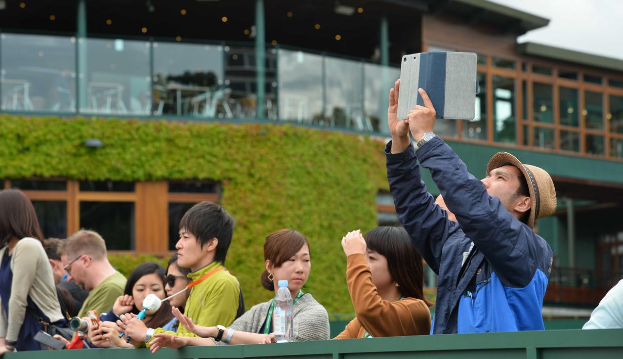 Penonton mengambil gambar suasana lapangan sebelum menonton Tenis Wimbledon Championships 2016 di The All England Lawn Tennis Club, Wimbledon,  London, (27/6/2016). (AFP/Glyn Kirk)