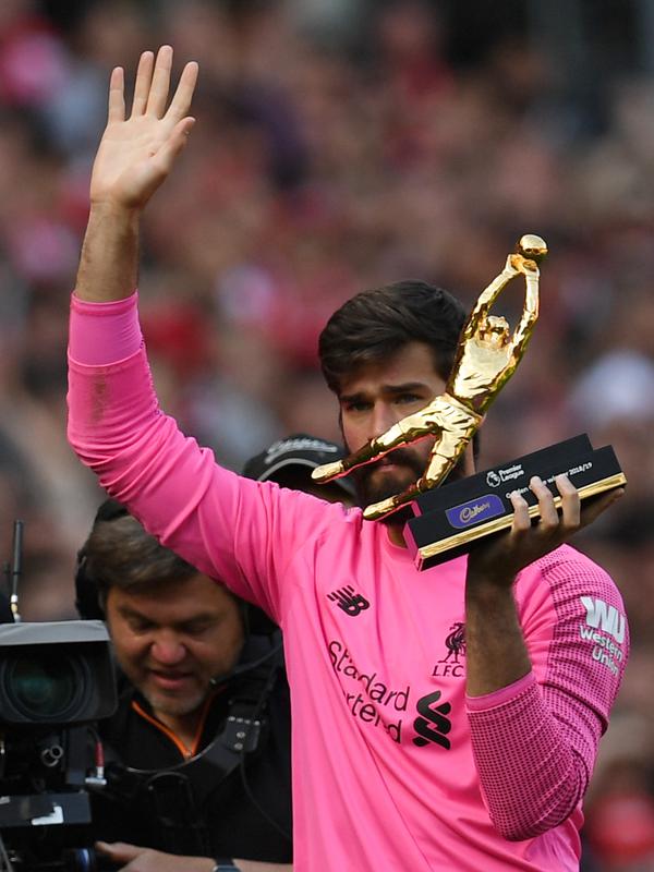 Kiper Liverpool, Alisson Becker menyapa para fans saat memegang penghargaan Golden Gloves usai pertandingan melawan Wolverhampton Wanderers pada lanjutan Liga Inggris di Anfield, Inggris (12/5/2019). Alisson mencatatkan 21 clean sheet di sepanjang musim ini. (AFP Photo/Paul Ellis)