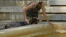 Seorang perempuan memercikkan air dari kolam ke anjingnya selama cuaca panas di Madrid, Spanyol, Rabu (13/7/2022). Ramalan cuaca setempat mengatakan Spanyol diperkirakan akan mengalami gelombang panas kedua dalam waktu kurang dari sebulan dan itu akan berlangsung setidaknya sampai akhir pekan. (AP Photo/Paul White)