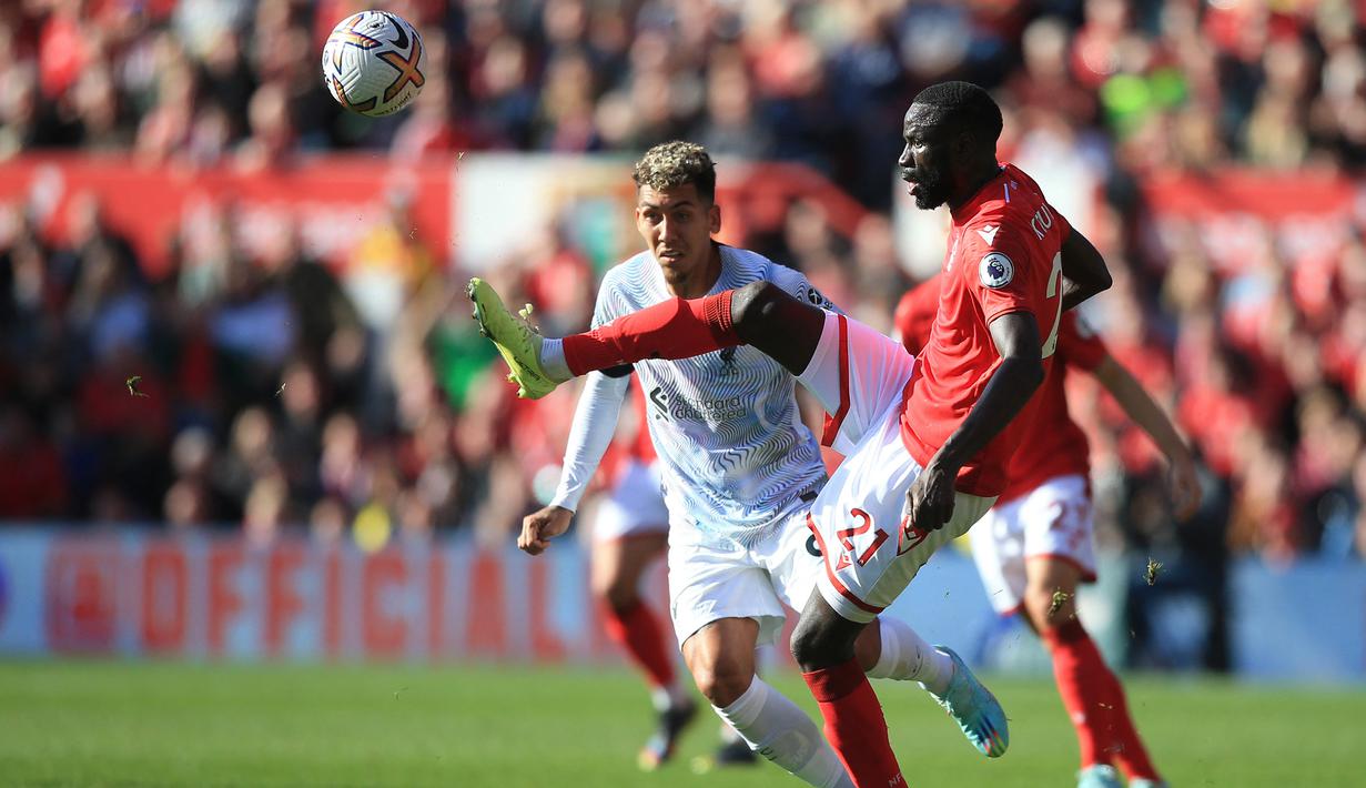 Gelandang Nottingham Forest, Cheikhou Kouyate menguasai bola di depan striker Liverpool, Roberto Firmino pada laga Liga Inggris 2022/2023 di City Ground, Nottingham (22/10/2022). Pemain asal Senegal ini didatangkan Nottingham Forest dari Crystal Palace pada awal musim 2022/2023 secara gratis dan dikontrak selama 2 tahun hingga Juni 2024. Di Liga Inggris 2022/2023 ia telah bermain 12 kali dengan torehan 1 gol. (AFP/Lindsey Parnaby)
