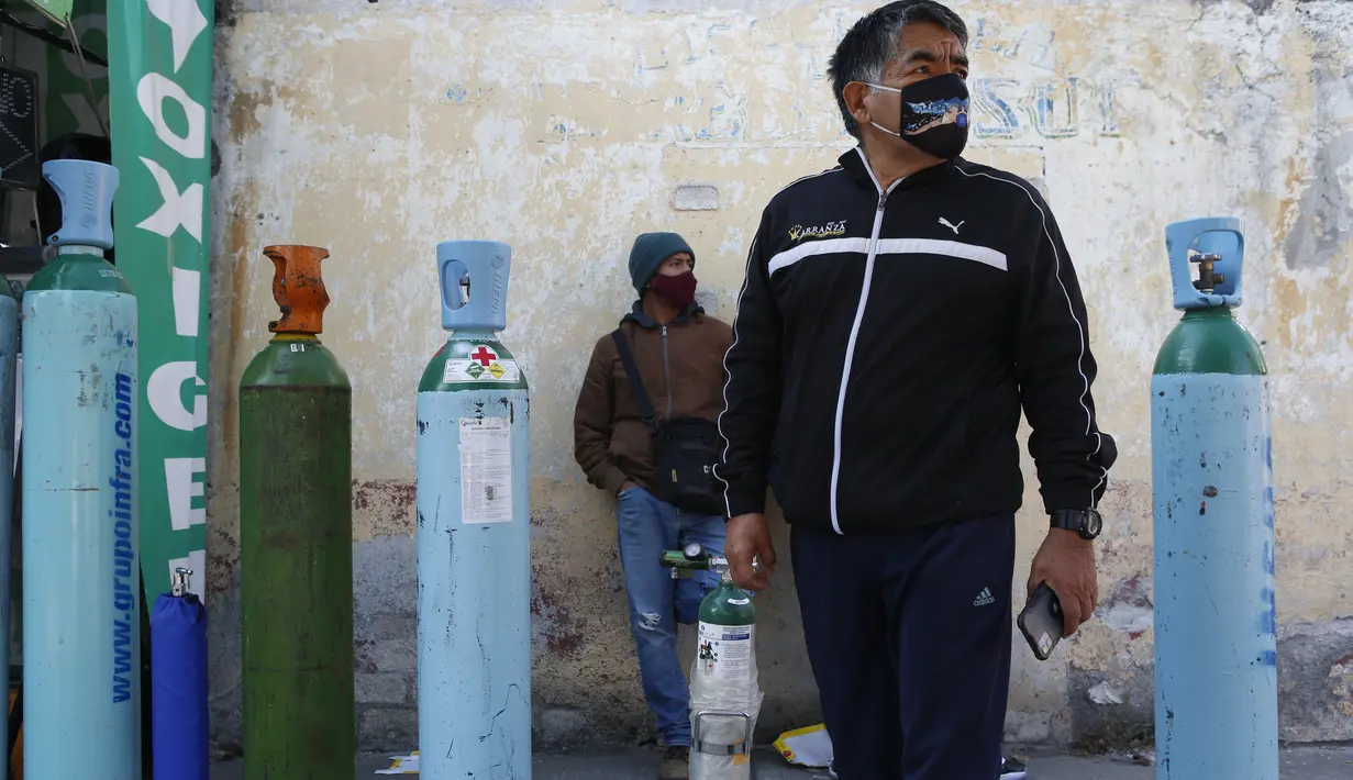 Jorge Perez antre mengisi tangki oksigen untuk anggota keluarga yang sakit COVID-19 di Mexico City pada 27 Desember 2020. Lonjakan pasien yang dirawat karena infeksi virus corona di Mexico City membuat toko pasokan medis kekurangan pasokan isi ulang tabung oksigen. (AP Photo/Ginnette Riquelme)