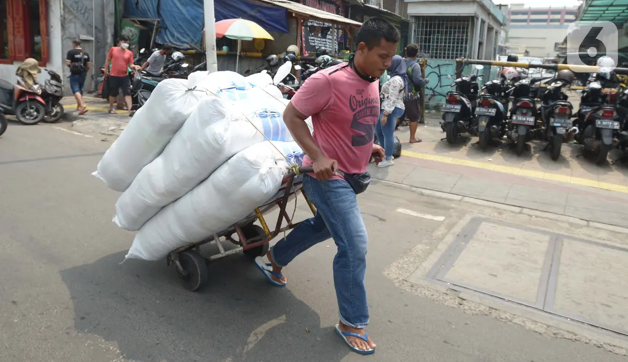 Seorang porter membawa pakaian jadi yang di kemas di karung di Kawasan Tanah Abang, Jakarta, Senin (11/10/2021). Menurunnya level PPKM jakarta menjadi level 3 membawa berkah bagi para kuli panggung dikarenakan geliat pasar tersebut kembali berjalan. (Liputan6.com/Angga Yuniar)