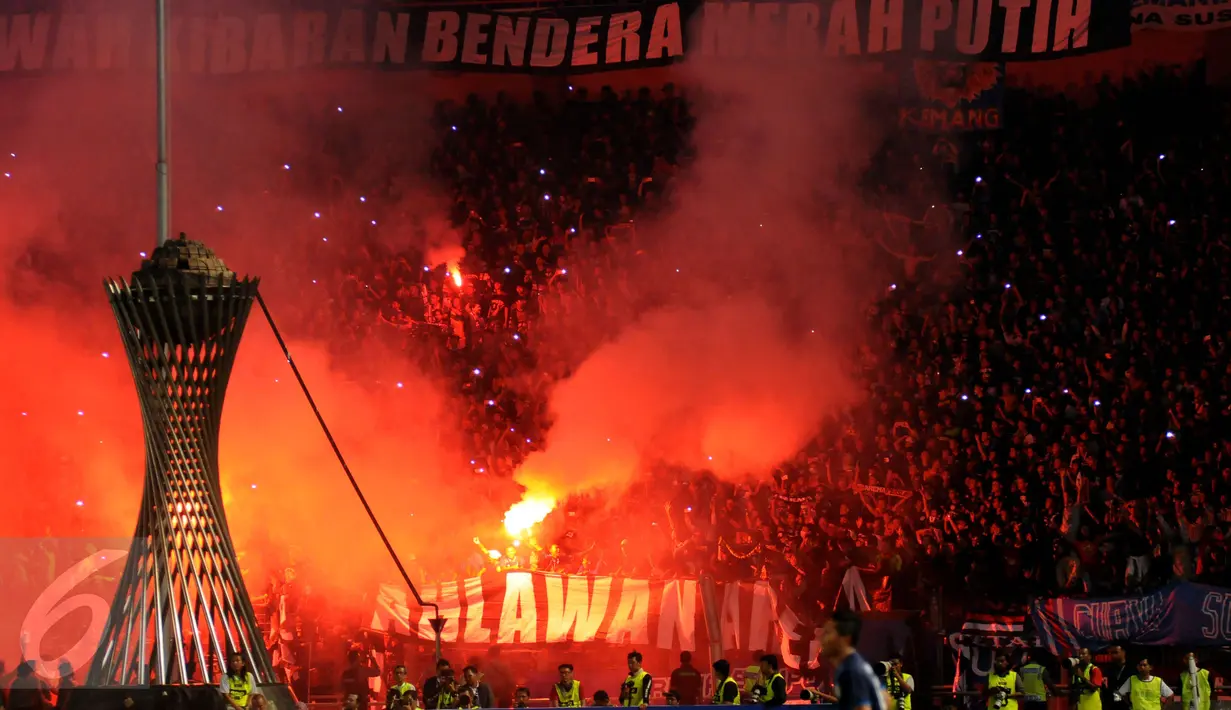 Suporter Arema Cronus menyalakan flare saat merayakan kemenangan tim Singo Edan di laga final Piala Bhayangkara 2016 melawan Persib di Stadion GBK Jakarta, Minggu (3/4/2016). Arema Cronus unggul 2-0 atas Persib. (Liputan6.com/Helmi Fithriansyah)