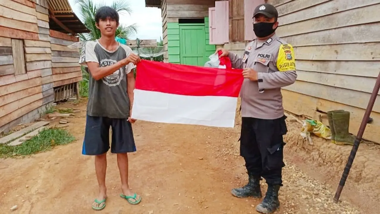 Suku Talang Mamak menerima bendera merah putih yang diberikan personel Polres Indragiri Hulu.