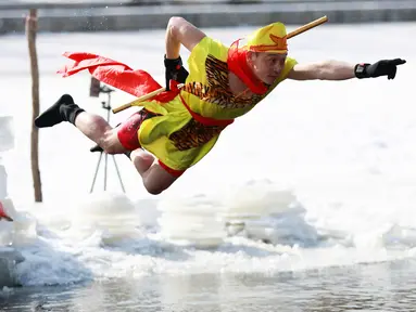 Seorang pria saat melompat ke danau yang beku di Shenyang di provinsi Liaoning, China timur laut (2/3). (AFP Photo)