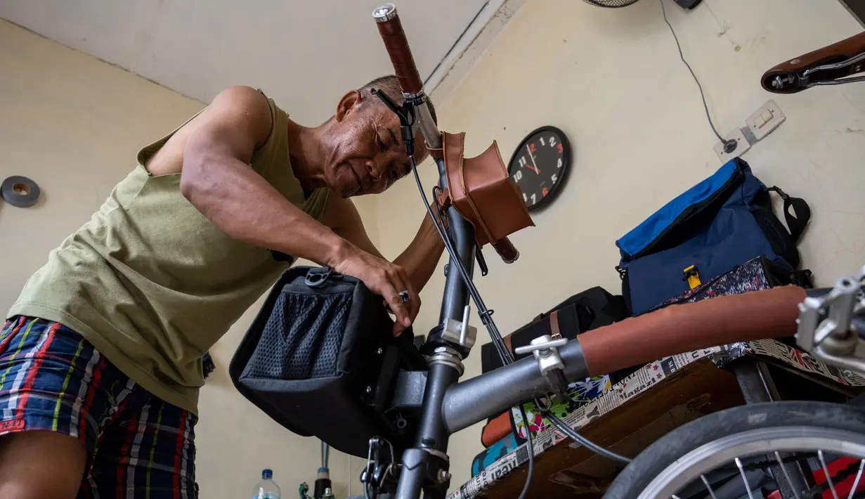 Taylor Amin Robert melakukan test-fit sebuah tas sepeda buatan tangannya di rumahnya, Jakarta (18/2/2020). Taylor yang otodidak memulai karirnya 30 tahun lalu, sekarang berspesialisasi dalam tas sepeda, dengan mayoritas klien mengendarai sepeda lipat di jalan-jalan kota. (AFP/Bay Ismoyo)