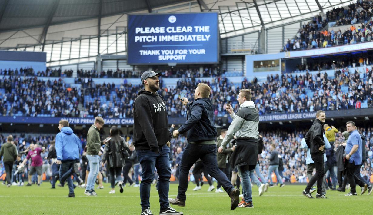 Suporter Manchester City berlari memasuki lapangan usai laga Manchester City melawan Swansea City pada lanjutan Premier League di Etihad Stadium, Manchester, (22/4/2018). Manchester City menang 5-0. (AP/Rui Vieira)