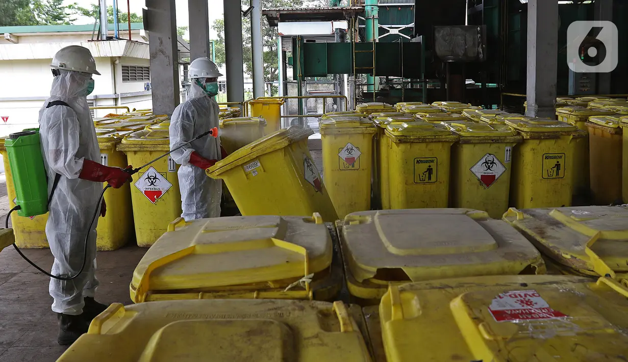 Petugas menyemprotkan cairan disinfektan pada "Wheeled Bin" atau tempat sampah berisi limbah B3 medis Infeksius Covid-19 usai dimusnahkan dengan mesin incinerator di PT Jasa Medivest, Karawang, Jawa Barat, Kamis (10/12/2020).  (Liputan6.com/Herman Zakharia)
