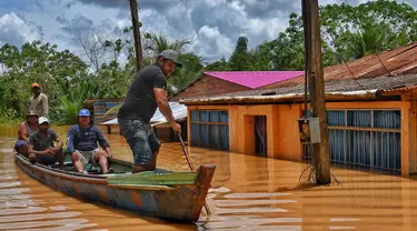 Orang-orang menaiki rakit di daerah yang terendam banjir setelah Sungai Acre meluap di Cobija, Bolivia, pada tanggal 29 Februari 2024. (STRINGER/AFP)