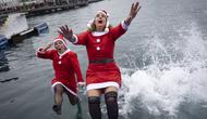 Sejumlah peserta berkostum Sinterklas melompat ke dalam air dalam ajang Copa Nadal yang berlangsung di Barcelona's Port Vell, Barcelona, Kamis (25/12/2025) waktu setempat. Acara tersebut diikuti lebih dari 450 peserta. (AFP/Josep Lago)