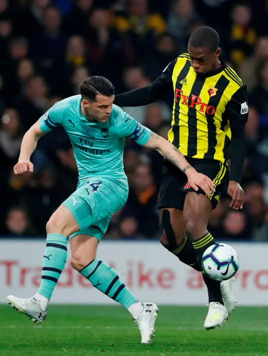 Gelandang Arsenal, Granit Xhaka berebut bola dengan  pemain Watford, Christian Kabasele dalam laga lanjutan Premier League 2018-19 pekan ke-34 di Vicarage Road, Senin (15/4). Arsenal sukses mengalahkan tuan rumah Watford dengan skor tipis 1-0. (Reuters / Matthew Childs)