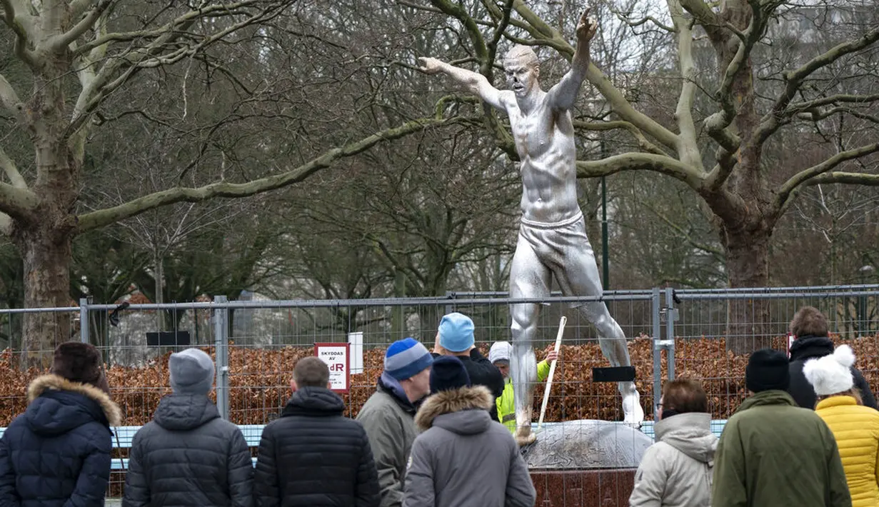 Sejumlah warga melihat patung Zlatan Ibrahimovic yang rusak di depan Stadion Malmo FF, Swedia, Minggu (22/12). Perusakan patung tersebut dilakukan fans Malmo karena kecewa sang idola berinvestasi di klub rival, Hammarby. (AP/Johan Nilsson)