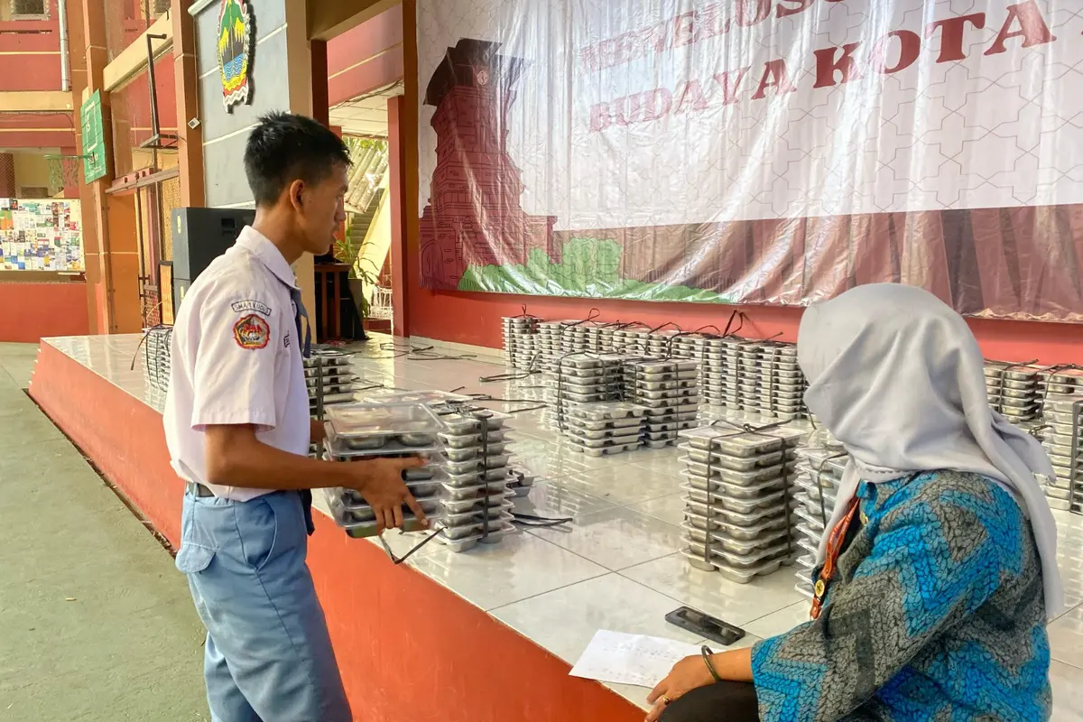 Salah satu siswa di SMA Negeri Kudus sedang mengambil kotak menu MBG. (Liputan6.com/Arief Pramono)