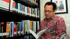Irman Gusman tampak membaca buku saat Liputan6.com berkunjung ke kediaman pribadinya, Jakarta, Rabu (3/12/2014). (Liputan6.com/Andrian M Tunay)