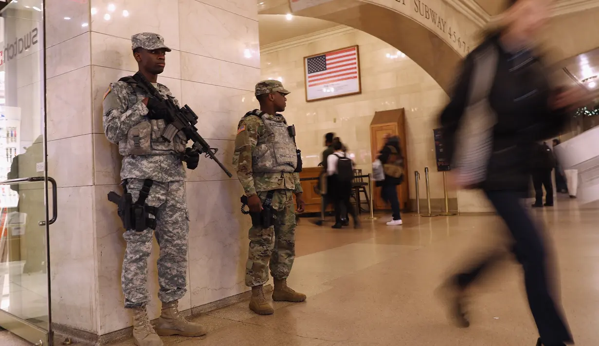 Pasukan Garda Nasional bersenjata laras panjang berjaga di terminal Grand Central, New York City, pasca teror bom pipa, Senin (11/12). Empat orang, termasuk pelaku dikabarkan mengalami luka-luka akibat teror bom tersebut. (JOHN MOORE / GETTY IMAGES / AFP)