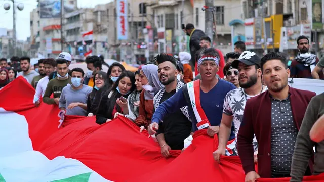 Pengunjuk rasa memegang bendera Irak ketika berlangsung demonstrasi pada Minggu, 1 Maret 2020.