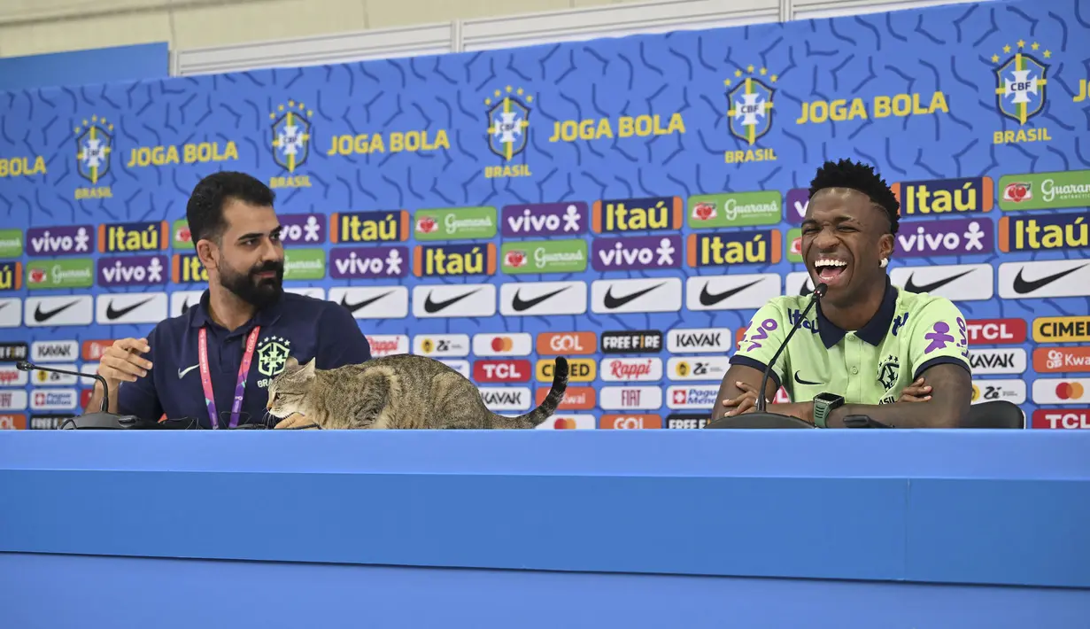 Ada seeokor kucing yang tiba-tiba menaiki meja yang ditempati Vinicius Junior dan staf media Timnas Brasil. (AFP/Nelson Almeida)