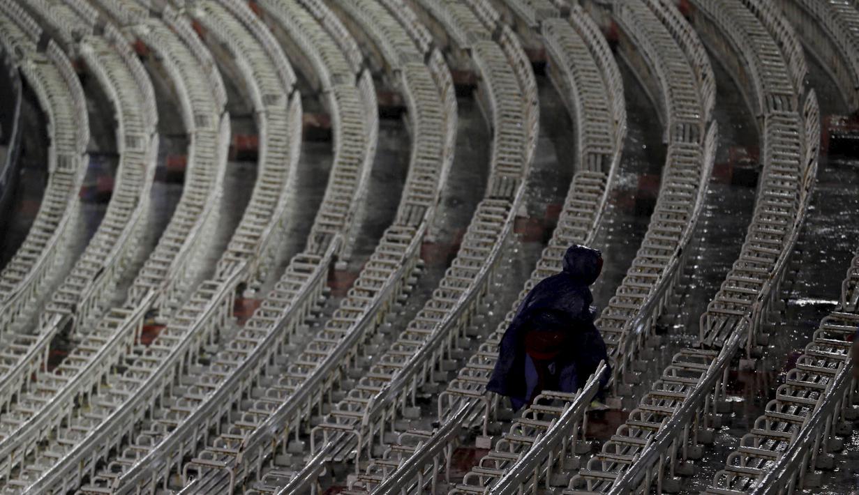 Seorang petugas memeriksa tribun Stadion Monumental, Buenos Aires, Argentina, ditengah hujan deras sebelum laga Kualifikasi Piala Dunia 2018 antara Argentina melawan Brasil. Jumat (13/11/2015) WIB. (Reuters/Marcos Brindicci)