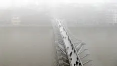 Pejalan kaki berjalan di atas jembatan Millennium Katedral di London, Senin, (23/1). Ribuan penumpang pesawat di Bandara Heathrow terpaksa ditunda keberangkatannya karena cuaca buruk ini. (AP Photo / Kirsty Wigglesworth)