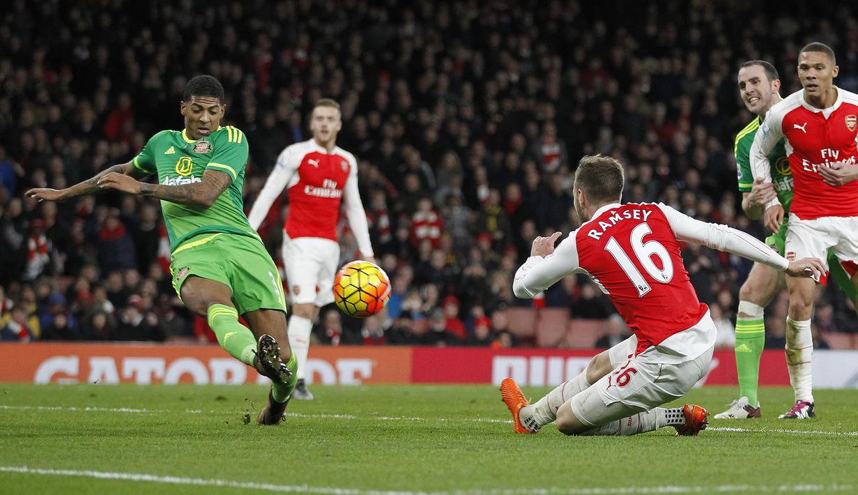 Pemain Sunderland, Patrick van Aanholt (kiri) melakukan tembakan saat dihadang pemain Arsenal  Aaron Ramsey pada lanjutan Liga  Premier Inggris di Stadion Emirates, London, Sabtu (5/12/2015). (AFP Photo/Ikimages) 