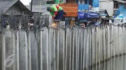 Seorang pekerja menyelesaikan pemasangan turap Kali Gendong di Penjaringan, Jakarta, Senin (10/10). Normalisasi kawasan bantaran kali Gendong saat ini terus dikerjakan sebagai bagian dari normalisasi kawasan Waduk Pluit. (Liputan6.com/Gempur M Surya)
