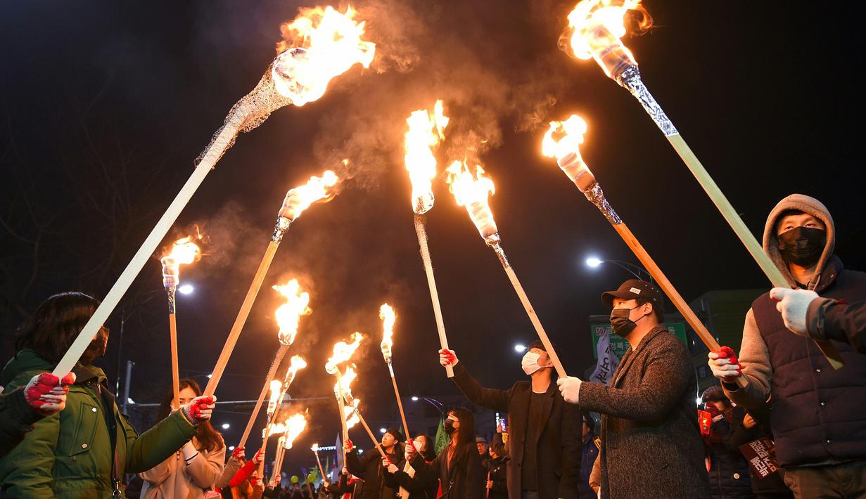 Sejumlah pengunjuk rasa membawa obor saat melakukan long march menuju kantor kepresidenan Rumah Biru, Seoul, Korea Selatan, Sabtu (3/12). (AFP/Jung Yeon-Je)