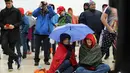 Warga berpayung saat menunggu di National Mall, Washington DC, untuk menyaksikan langsung pelantikan Trump, AS, Jumat (20/1).(AFP Photo)