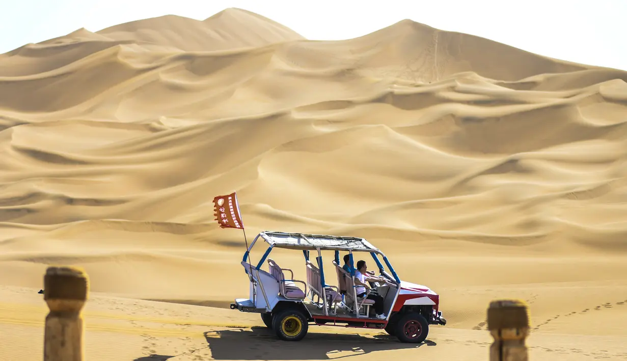 Para wisatawan menjelajahi kawasan wisata Gurun Kum Tag dengan sebuah kendaraan di Wilayah Shanshan, Kota Turpan, Daerah Otonom Uighur Xinjiang, China barat laut (22/9/2020). Gurun tersebut saat ini mencatat peningkatan arus wisatawan. (Xinhua/Wang Fei)